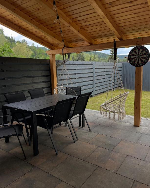 a patio with a table and chairs and a swing at RIA Duplex Ariniș in Gura Humorului
