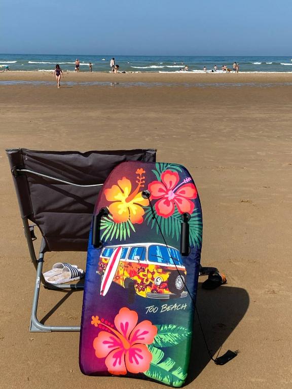 une chaise et une planche de surf sur la plage dans l'établissement Appartement 1 chambre et cuisine VIERVILLE-SUR-MER,plage du Débarquement, à Vierville-sur-Mer