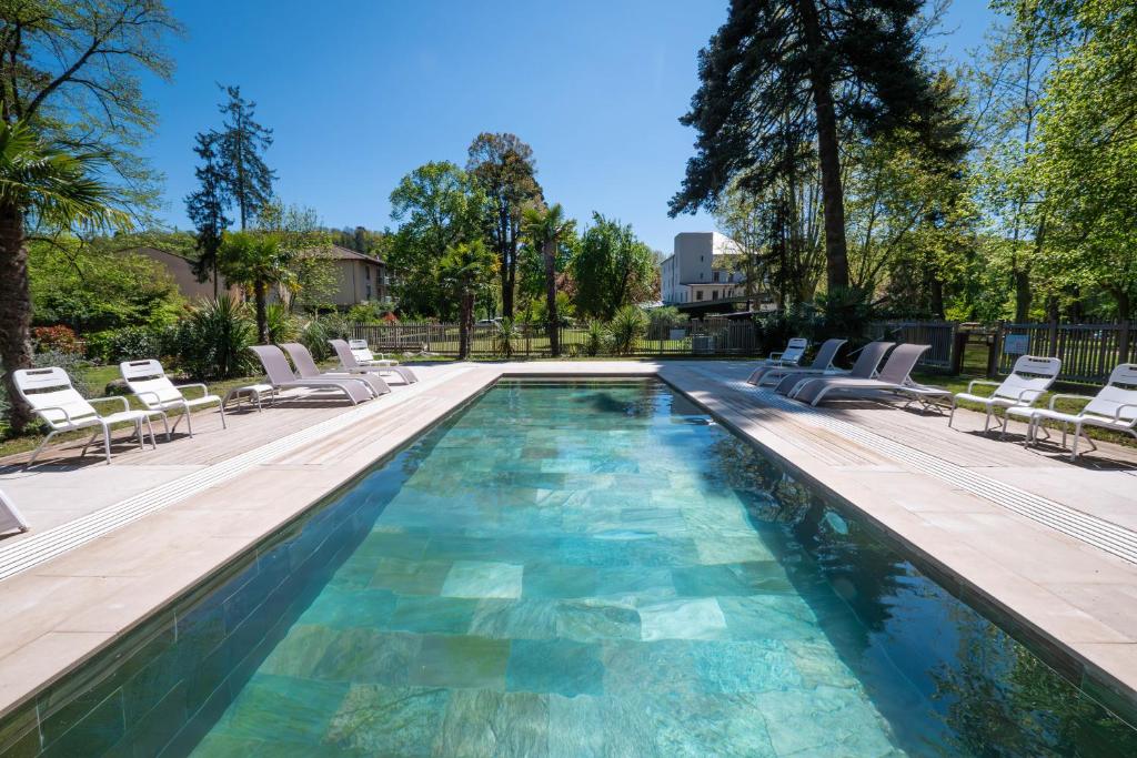 a swimming pool with chaises and chairs in a yard at Domaine le Vaxergues in Saint-Affrique