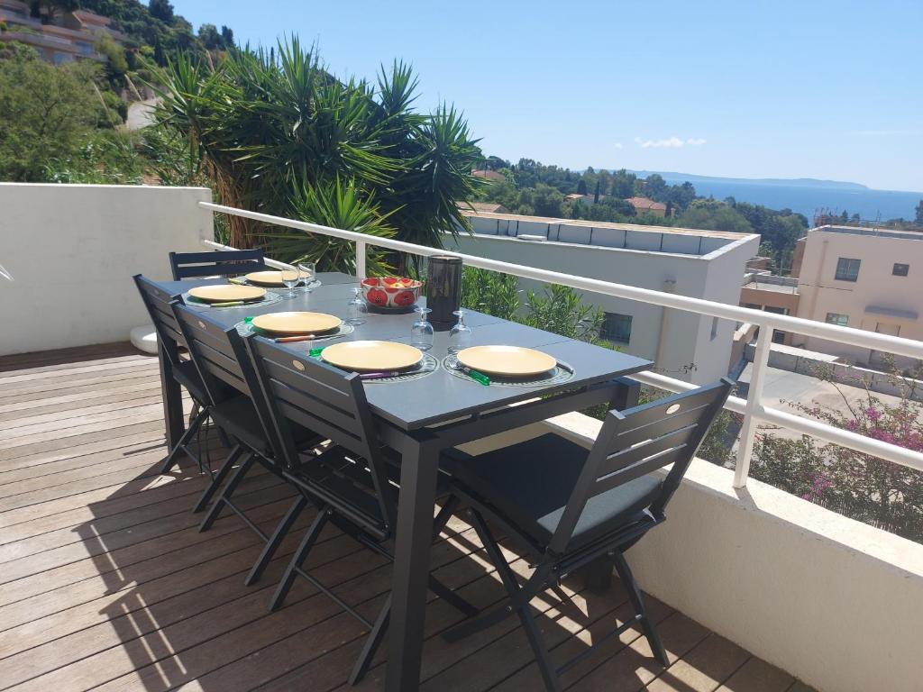 une table et des chaises sur un balcon avec vue dans l'établissement Haut de villa Vue mer, au Lavandou