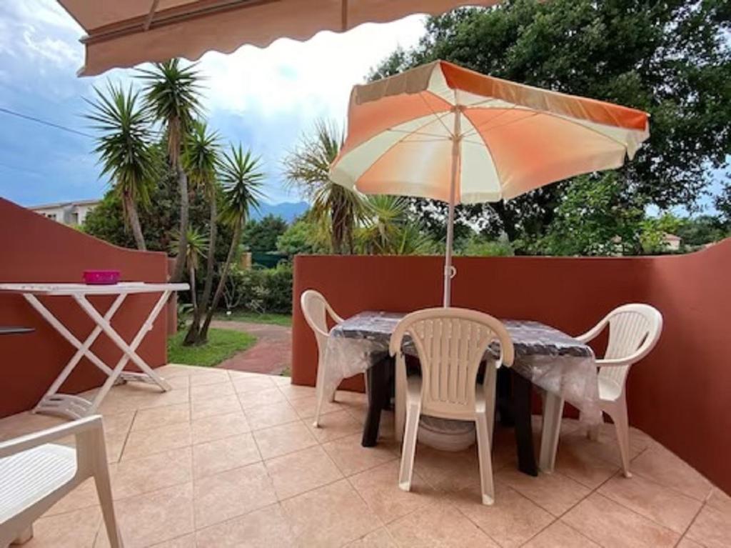 une table et des chaises avec un parasol sur une terrasse dans l'établissement MORIANI PLAGE Studio climatisé 4 pers B2, à Moriani-Plage
