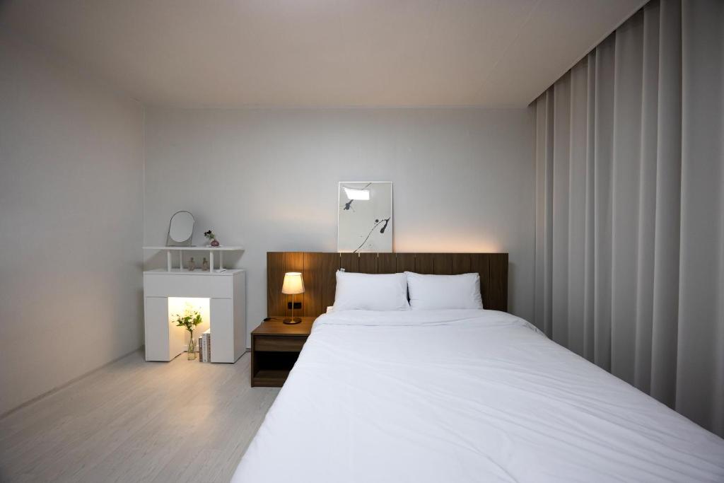 una camera da letto con un grande letto bianco e un tavolo di Big Star Stay a Busan