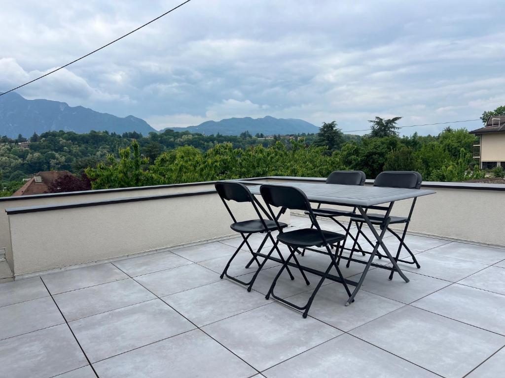 Una mesa y sillas en un balcón con vista. en Appartement T2, neuf, climatisé avec terrrasse, en Aix-les-Bains