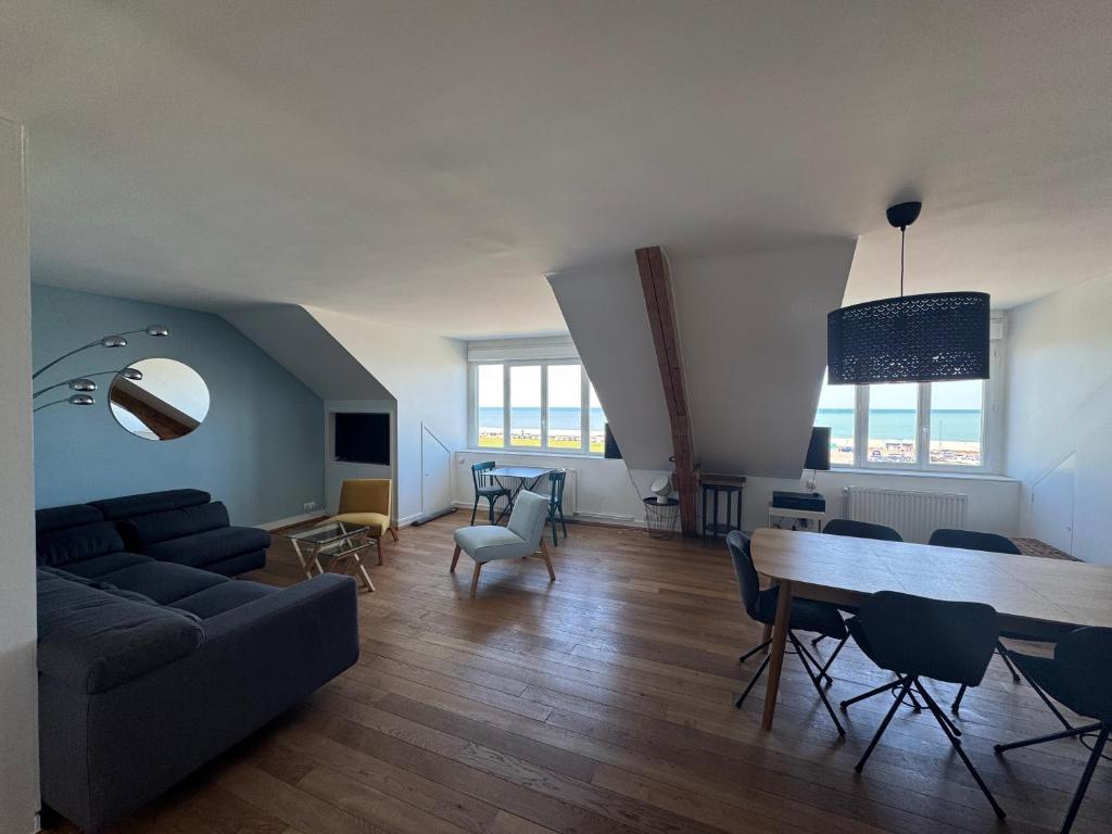 Una sala de estar con un sofá, una mesa y sillas. en Sunset Dieppe, en Dieppe