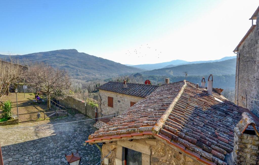 un edificio con tetto piastrellato e montagne sullo sfondo di Monteluce a Santa Fiora