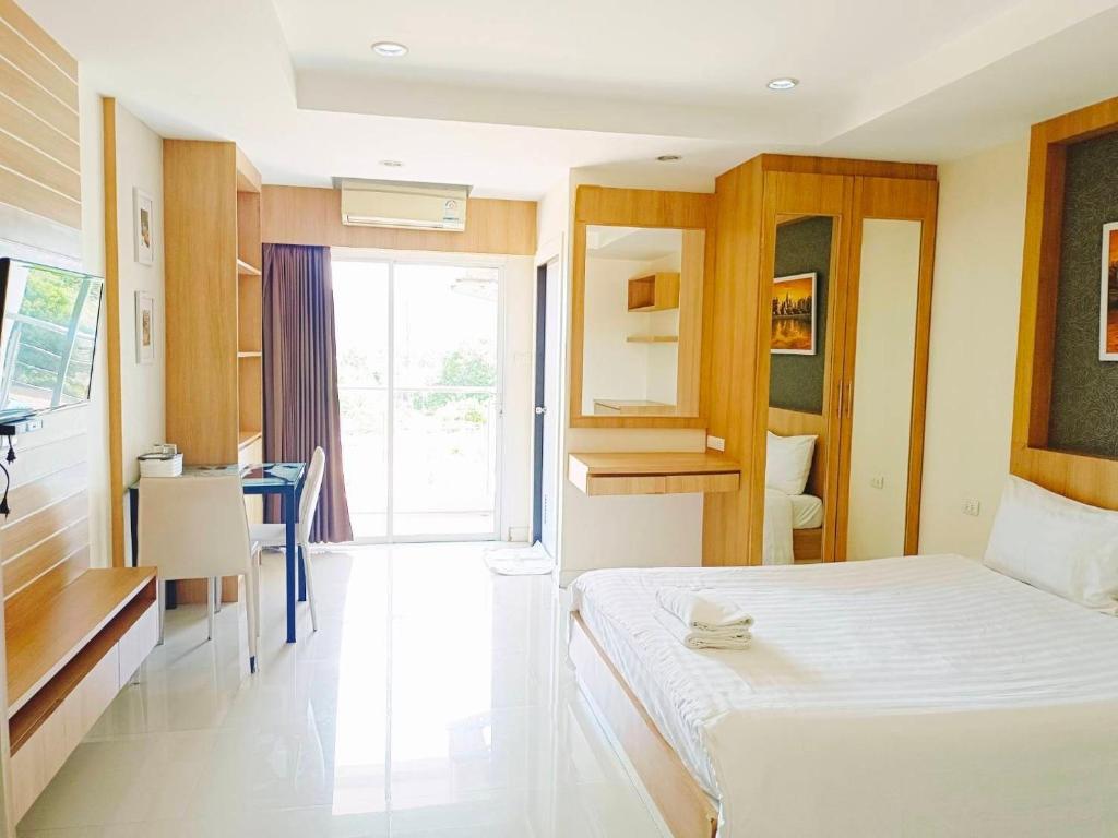a bedroom with a bed and a desk and a kitchen at Sea Hill Hotel Bangsaray in Bang Sare