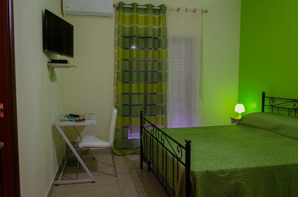 a green bedroom with a bed and a television at Civico 44 in Crotone