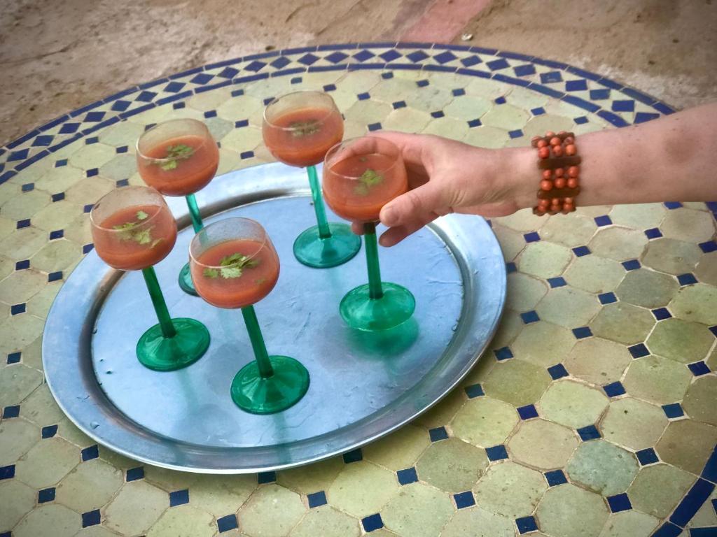 una persona tiene in mano un gruppo di bicchieri da vino su un tavolo di Hotel Carrefour des Nomades a M'Hamid
