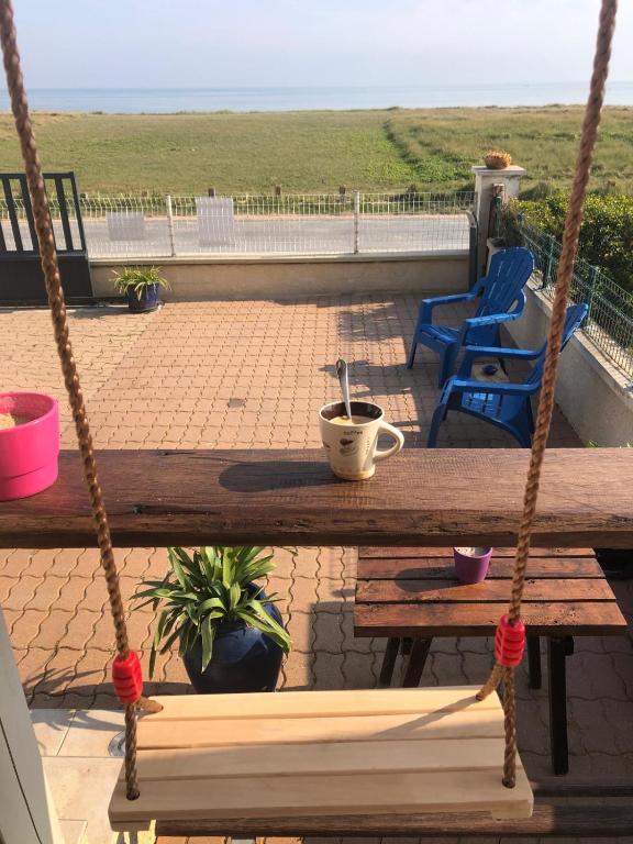 une balançoire en bois avec une table et une tasse à café dans l'établissement La vague salée, à Hermanville-sur-Mer