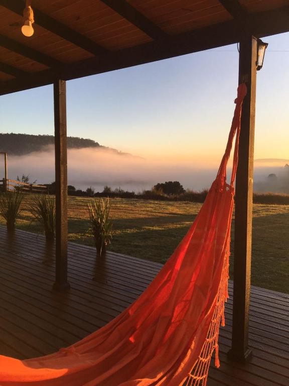 a hammock on a deck with the sunset in the background at Rancho do Tigre in São Joaquim