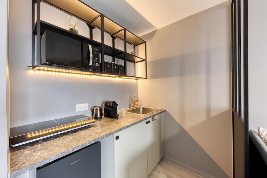 une cuisine avec un évier et un micro-ondes dans l'établissement Charmant Studio 15 minutes from Paris, à Rosny-sous-Bois