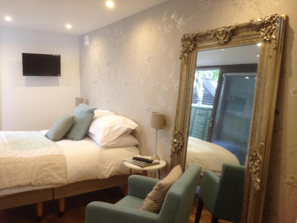 a bedroom with a bed and a mirror and chairs at The Studio in Newmarket