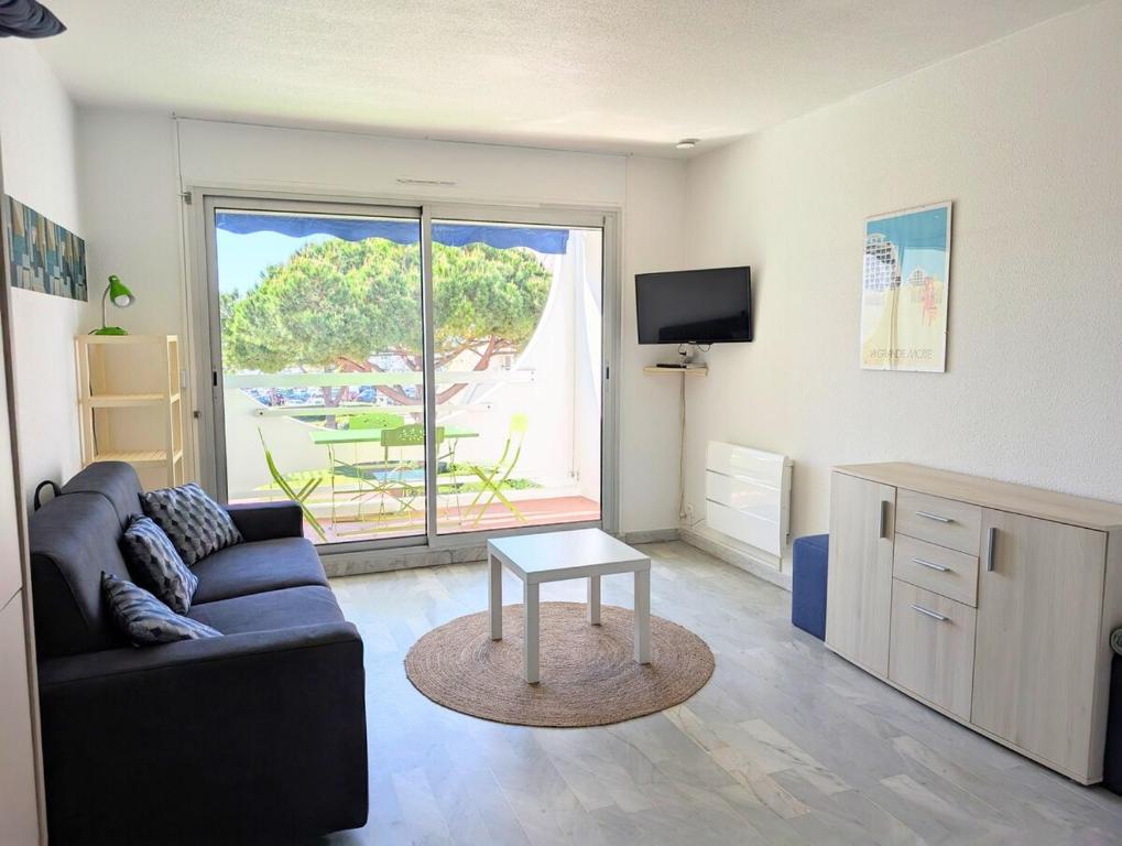 a living room with a couch and a table at Centre ville, studio vue port, avec parking privé in La Grande-Motte