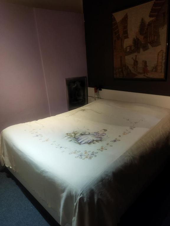 łóżko z białym prześcieradłem i obrazkiem na nim w obiekcie Loft 70 w mieście Montescudaio