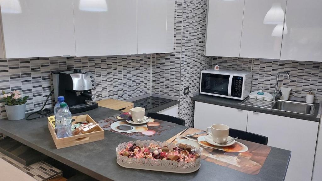 a kitchen with white cabinets and a table with food and drinks at Casa Ohana a home a dream in Como