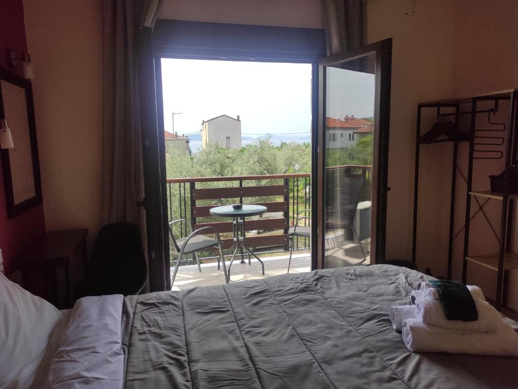 a bedroom with a bed and a balcony with a table at Poseidon Rooms in Kala Nera
