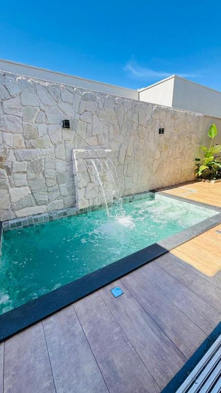 a swimming pool with a waterfall in a stone wall at Casa Samambaia in Goiânia