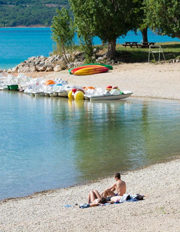 deux personnes allongées sur la plage au bord de l'eau dans l'établissement MOBIL HOME DANS CAMPING 3 etoiles GORGES DU VERDON CALME 4 PERS PLANCHA, à Sainte-Croix-de-Verdon