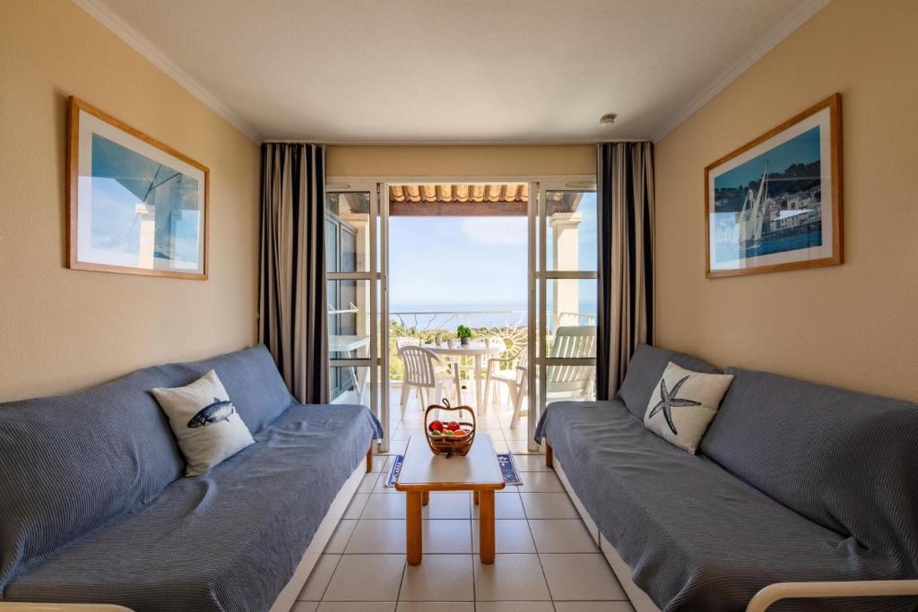 un salon avec deux canapés bleus et une table dans l'établissement Résidence le Hameau de Cap Esterel - maeva Home - Appartement 2 pièces 5 personnes - Confort MAE-5664, à Saint-Raphaël