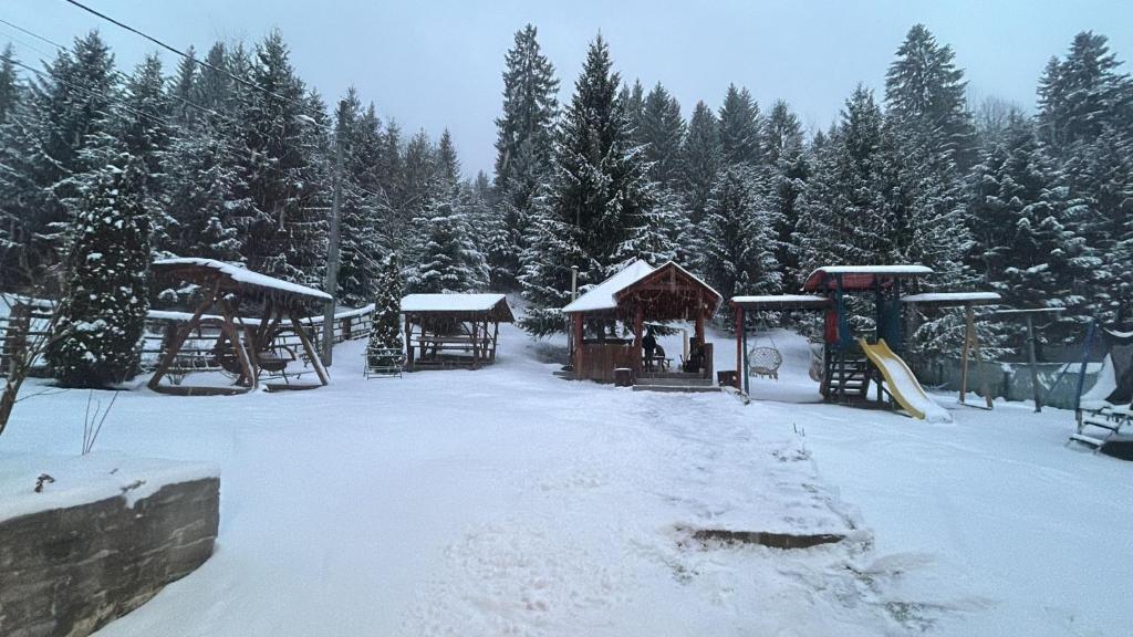 a snow covered park with a playground with a slide at Vila Eliza Voronet in Voronet