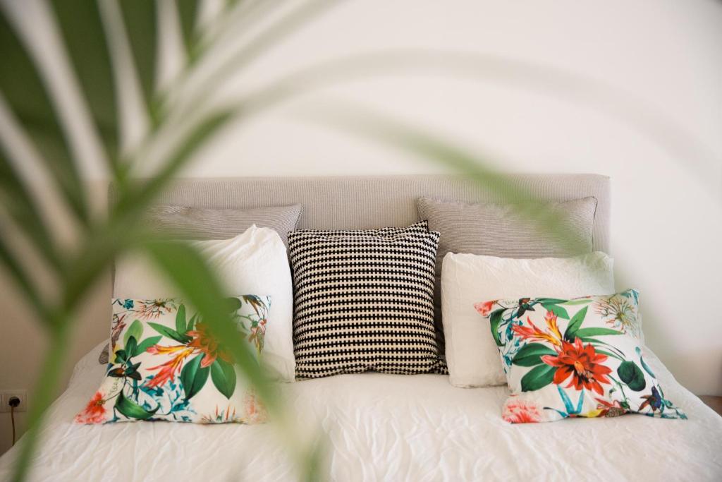 a white bed with four pillows and a plant at B&B Bloemgracht in Amsterdam