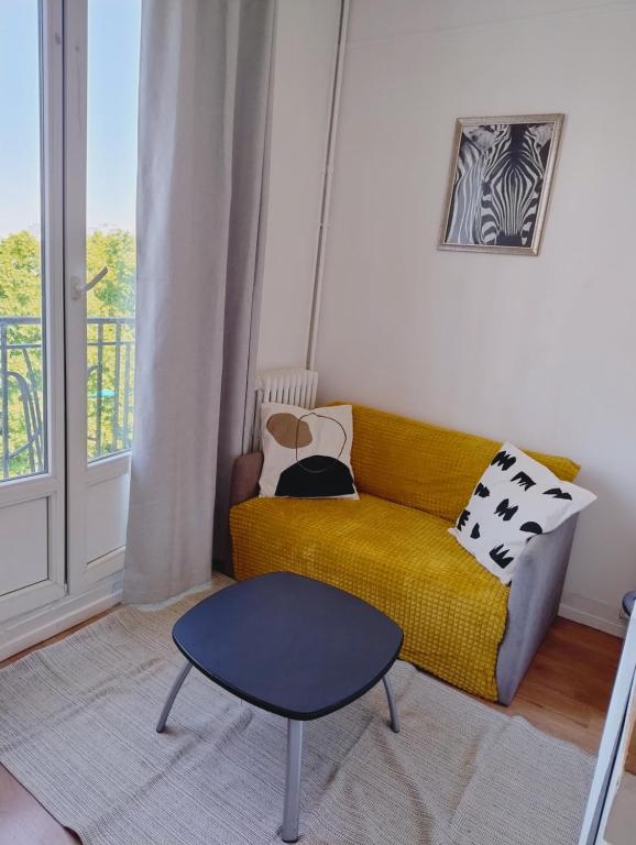 un salon avec un canapé jaune et une table dans l'établissement Studio cosy - proche Metro13 G Péri, à Gennevilliers
