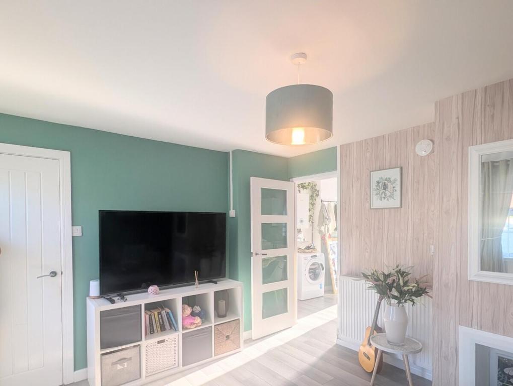 ein Wohnzimmer mit einem Flachbildfernseher an der Wand in der Unterkunft Family house near the beach! in Saint Columb Minor