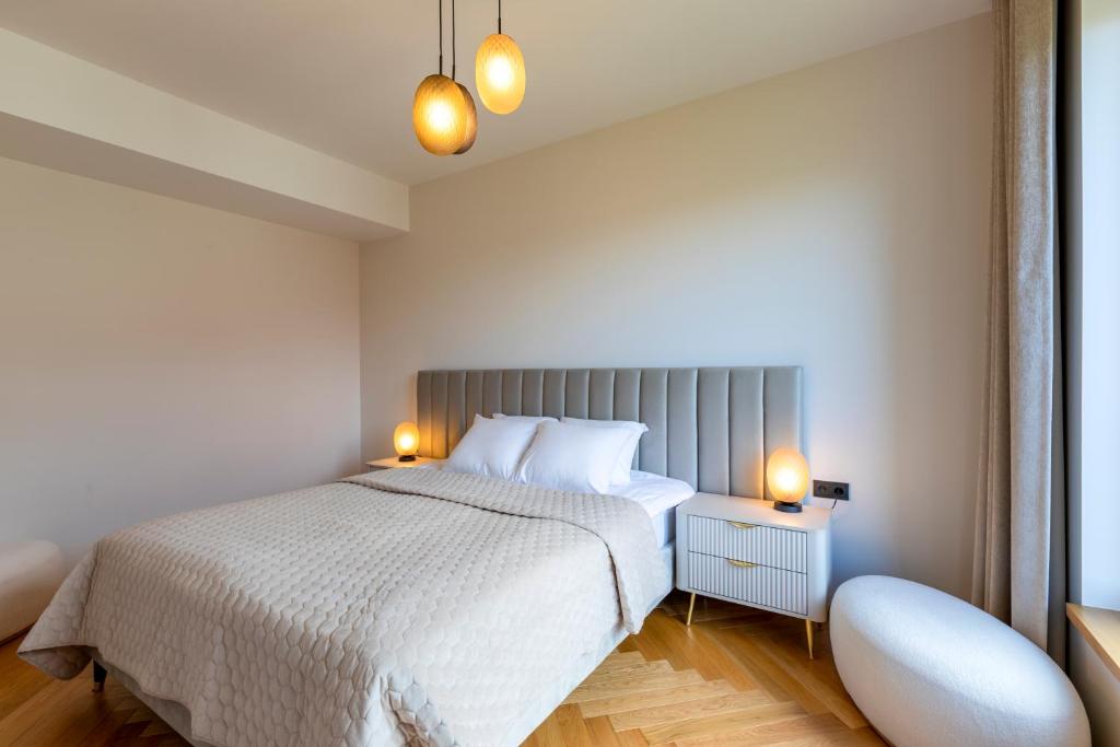 a bedroom with a white bed and two lamps at Heven Apartments Karusselli in Pärnu