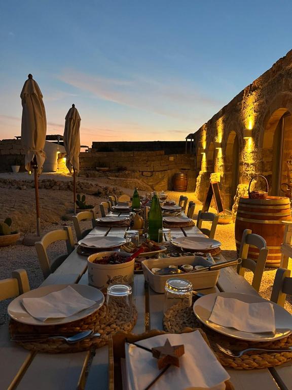 un lungo tavolo con piatti di cibo su una spiaggia di Masseria Specula a San Pietro in Bevagna