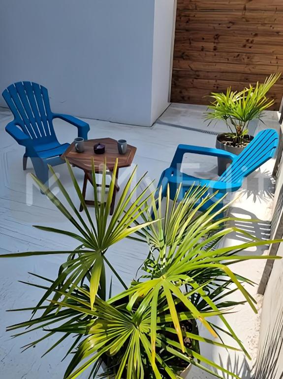 deux chaises bleues et une table et des plantes sur un porche dans l'établissement Appartement spacieux avec terrasse, Saint-Malo, Dinard, Dinan et Dol, à Miniac-Morvan