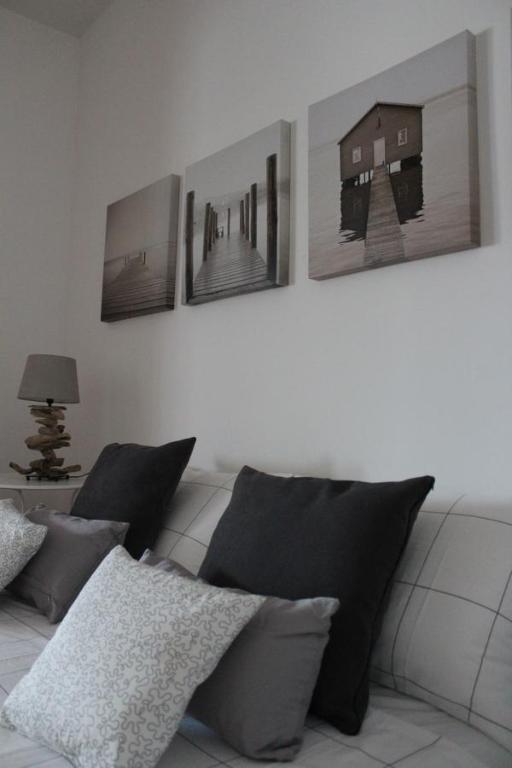 uma sala de estar com um sofá com quatro fotografias na parede em CircEea Beach B&B em San Felice Circeo
