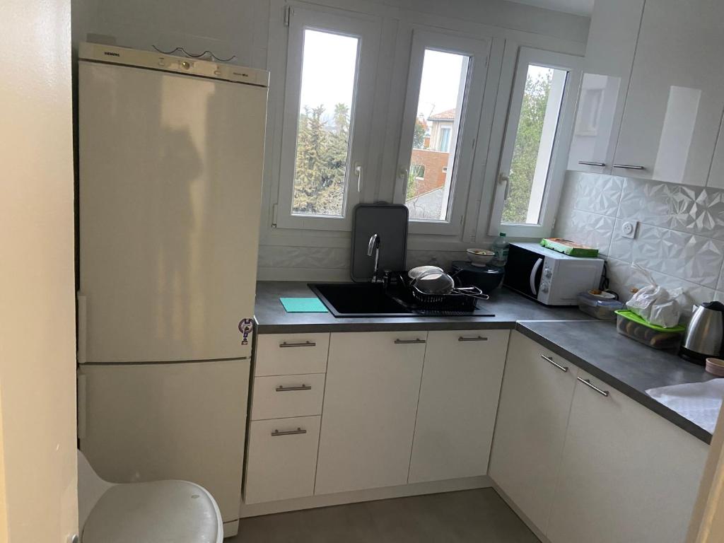 une cuisine avec des armoires blanches et un réfrigérateur blanc dans l'établissement Bien au calme, à La Celle-sous-Gouzon