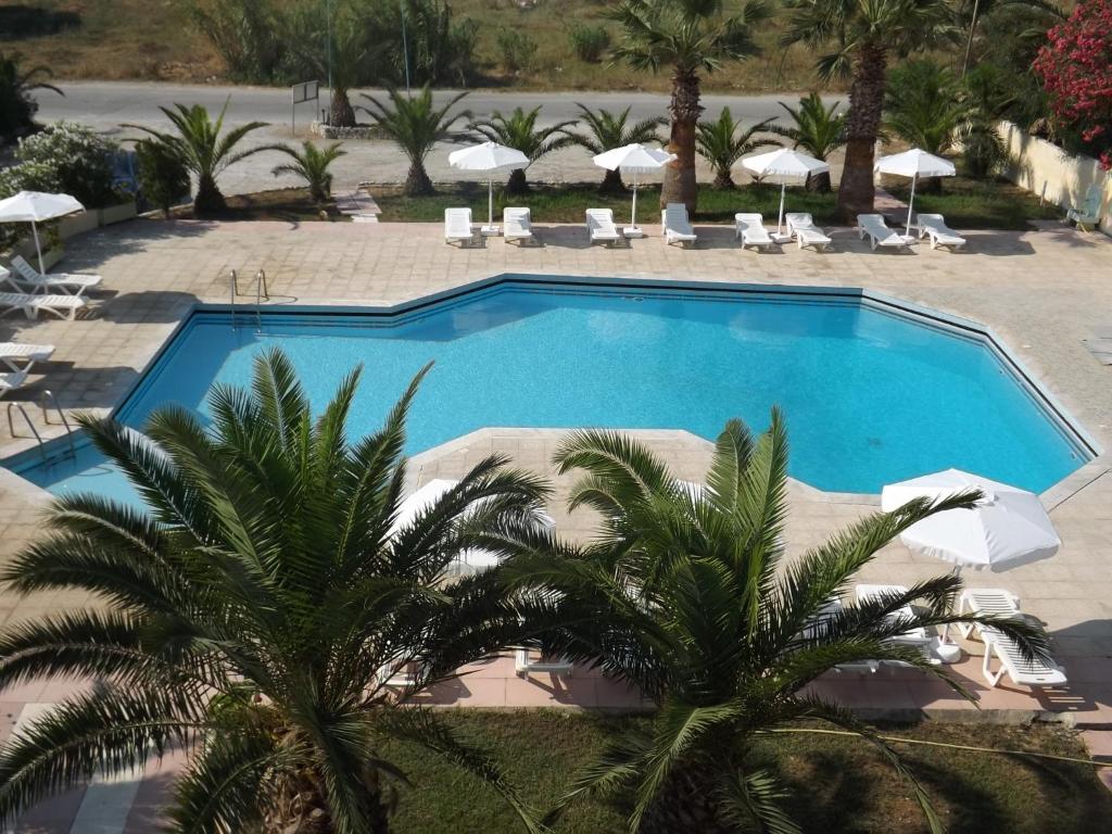 una piscina en un complejo con palmeras en Leonidas Hotel & Studios, en Cos