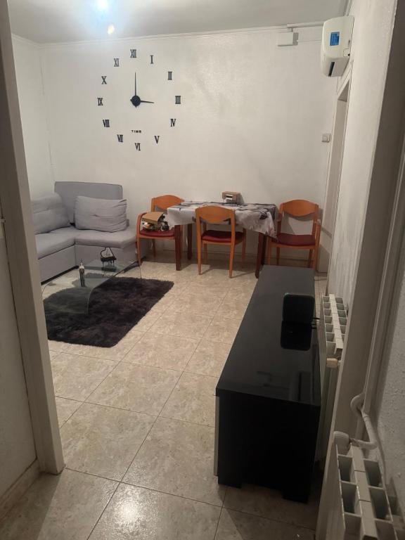 Una sala de estar con un sofá y un reloj en la pared. en Dormir sleep Comidad 100, en Barcelona