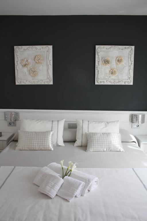 a white bed with two pillows in a room at Hotel Herreros in Castellón de la Plana