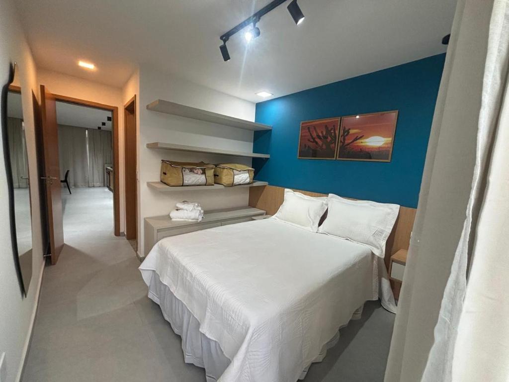 a bedroom with a white bed and a blue wall at Casa Aroeira Milagres in São Miguel dos Milagres