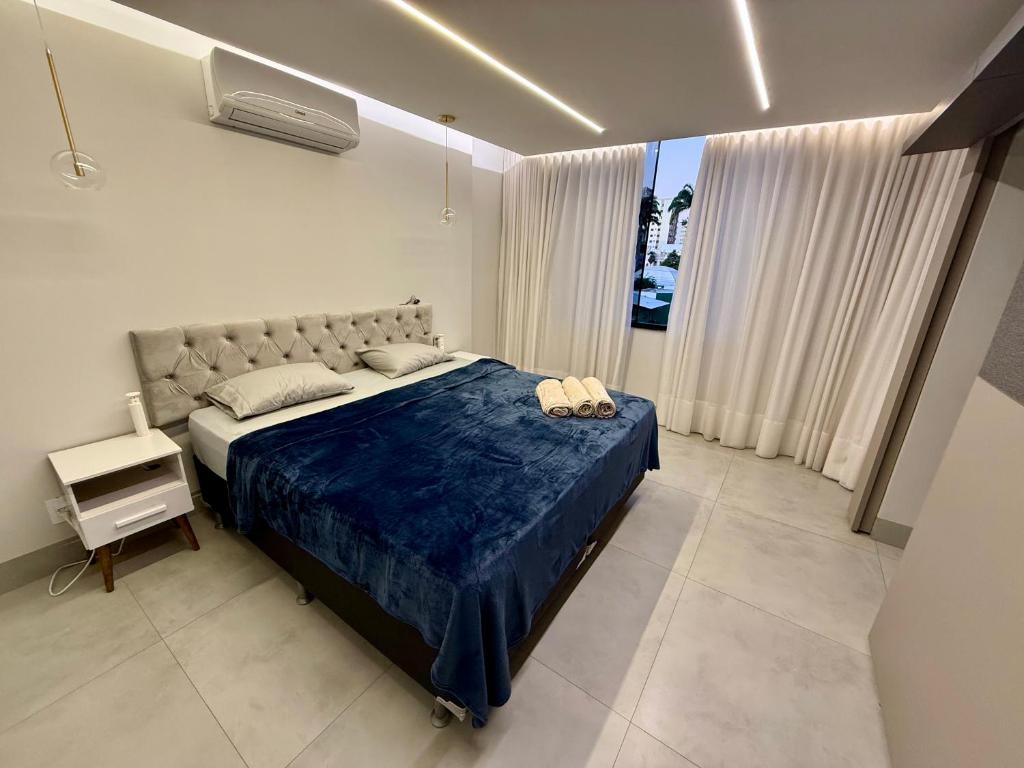 a bedroom with a large bed with a blue blanket at Apartamento Central de Luxo- Ar condicionado, wi-fi in Patos de Minas