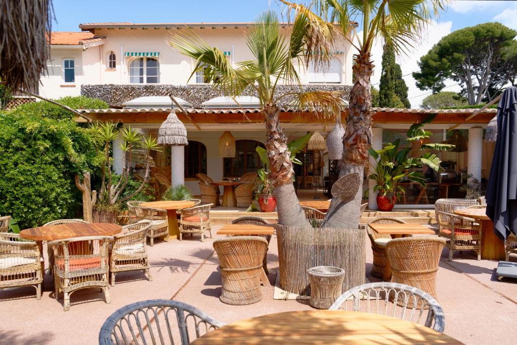 an outdoor patio with tables and chairs and palm trees at La Garoupe-Gardiole in Antibes