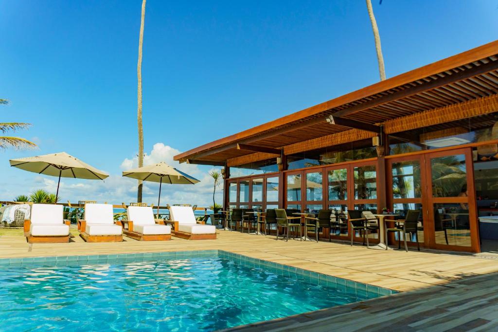 basen z krzesłami i parasolami obok budynku w obiekcie Pousada de Charme Refúgio da Villa w mieście Porto de Galinhas