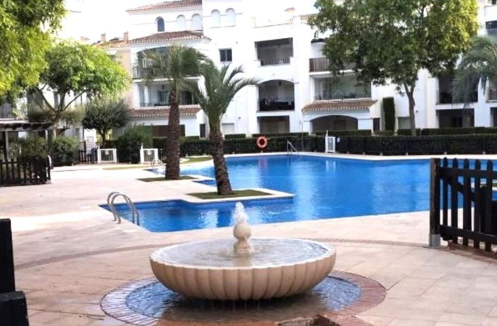 a fountain in front of a swimming pool with a building at Ground floor family apartment, Close to Town and pool in Casas del Cura