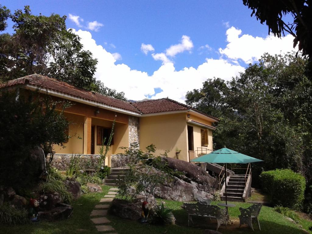 a house with a green umbrella in the yard at Pousada Chácara Pacheco in Visconde De Maua