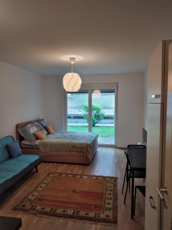 a bedroom with a bed and a couch and a window at BLR Apart in Graz
