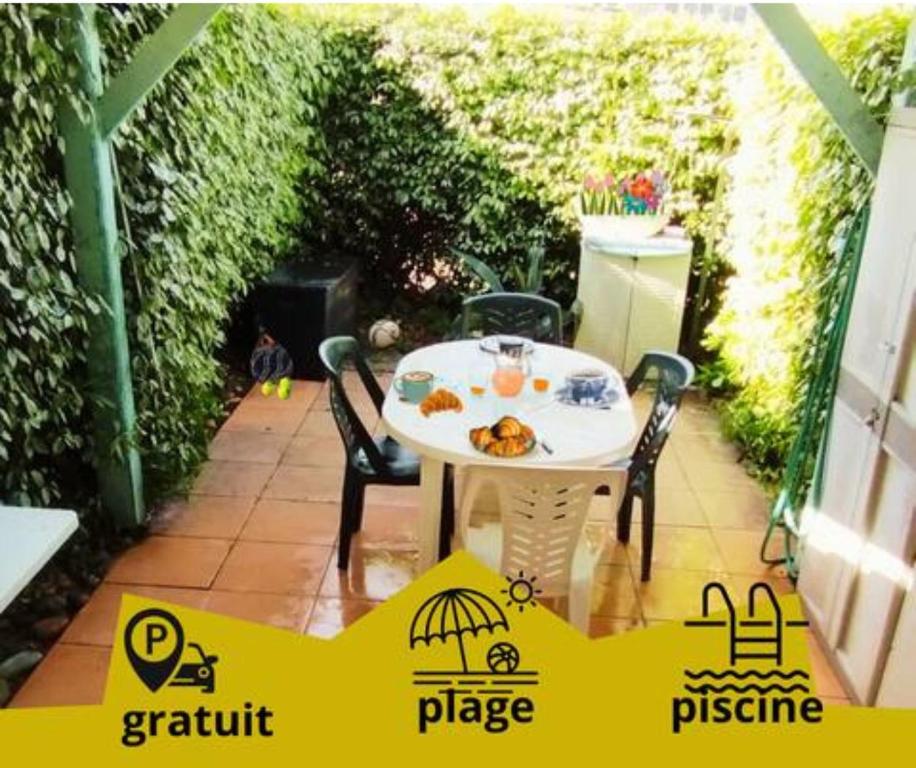 une table blanche et des chaises sur une terrasse dans l'établissement Villa Mimosa Côté Mer et Piscine, à Frontignan