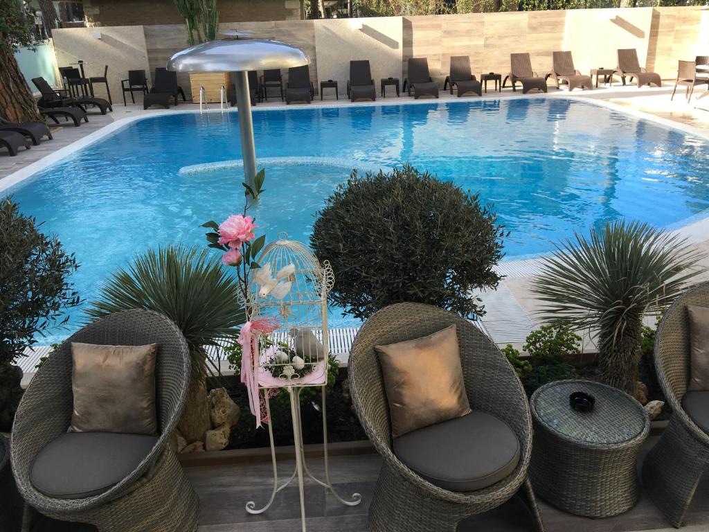 une grande piscine avec des chaises, une table et une table dans l'établissement Hotel Alexander, à Milano Marittima
