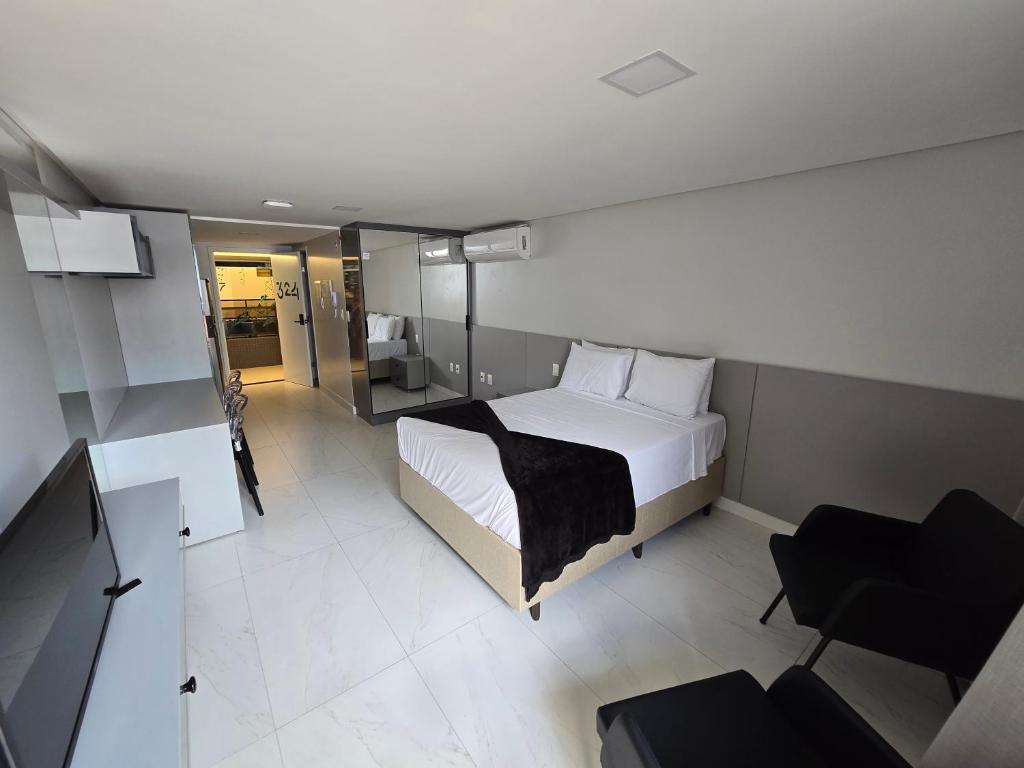 a hotel room with a bed and a chair at Unity, Cabo Branco Flat 324 in João Pessoa