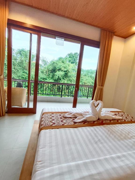 a bedroom with a bed and a large window at D'JERO HomeStay in Ubud