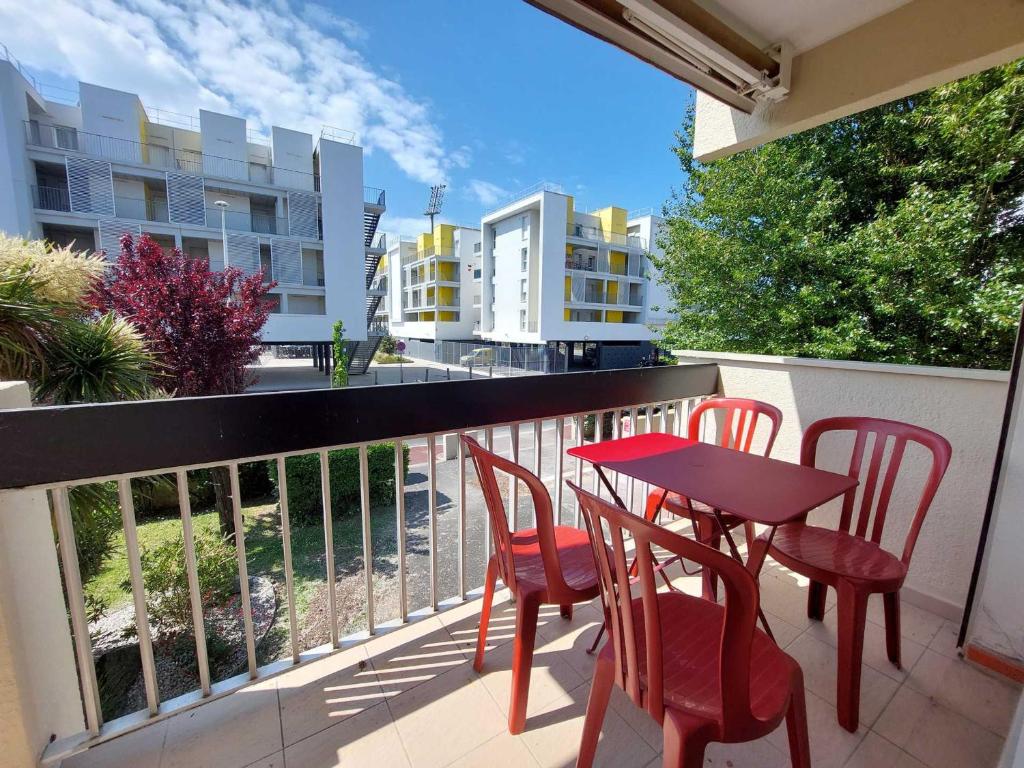 d'un balcon avec une table et des chaises rouges. dans l'établissement Spacieux 2 pièces avec balcon et parking proche gare, Royan - FR-1-550-93, à Royan