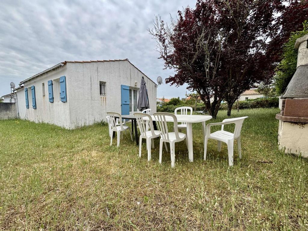 une table et des chaises dans l'herbe devant un bâtiment dans l'établissement Maison calme près de la plage, 5 personnes, parking inclus - FR-1-246A-352, à Saint-Georges-dʼOléron