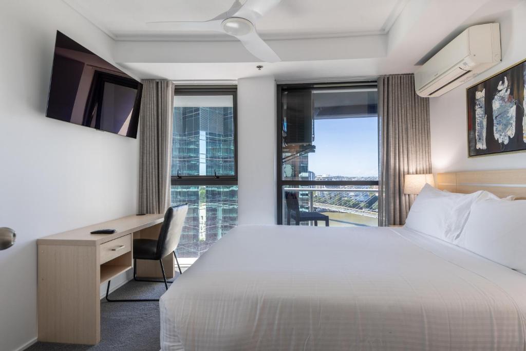 a hotel room with a bed and a desk and window at Private CBD Bedroom in a Shared Apartment on Brisbane River in Brisbane
