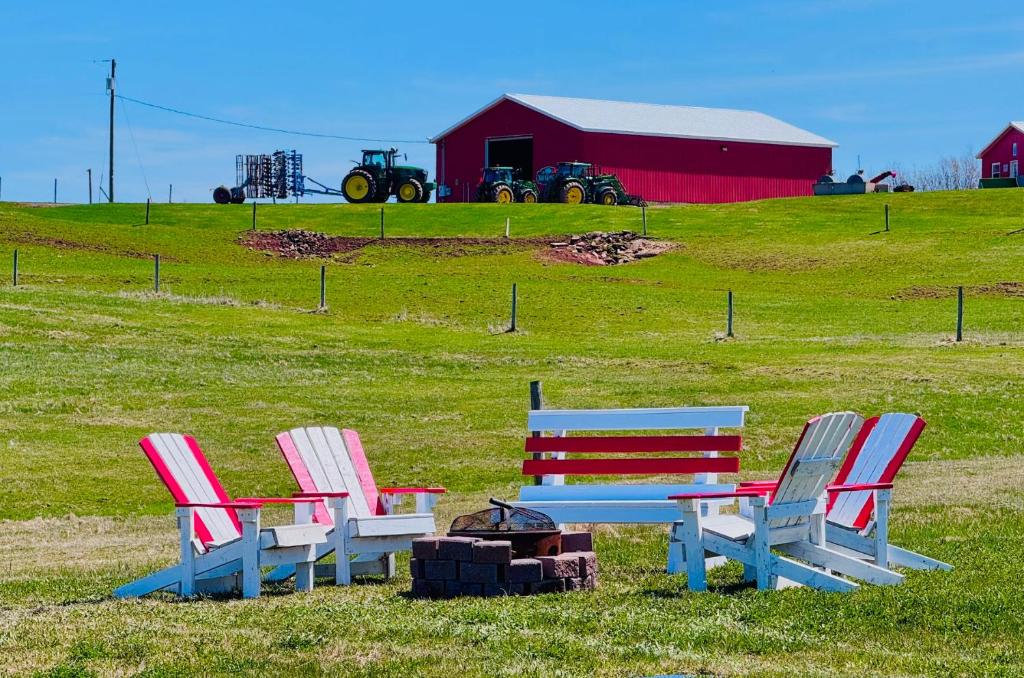 three chairs and a picnic table in a field with a red barn at Niseko Riverside By Zen Life 4Bedrooms Greenie Cottage and 3bedrooms Cowie Cottage in New Glasgow